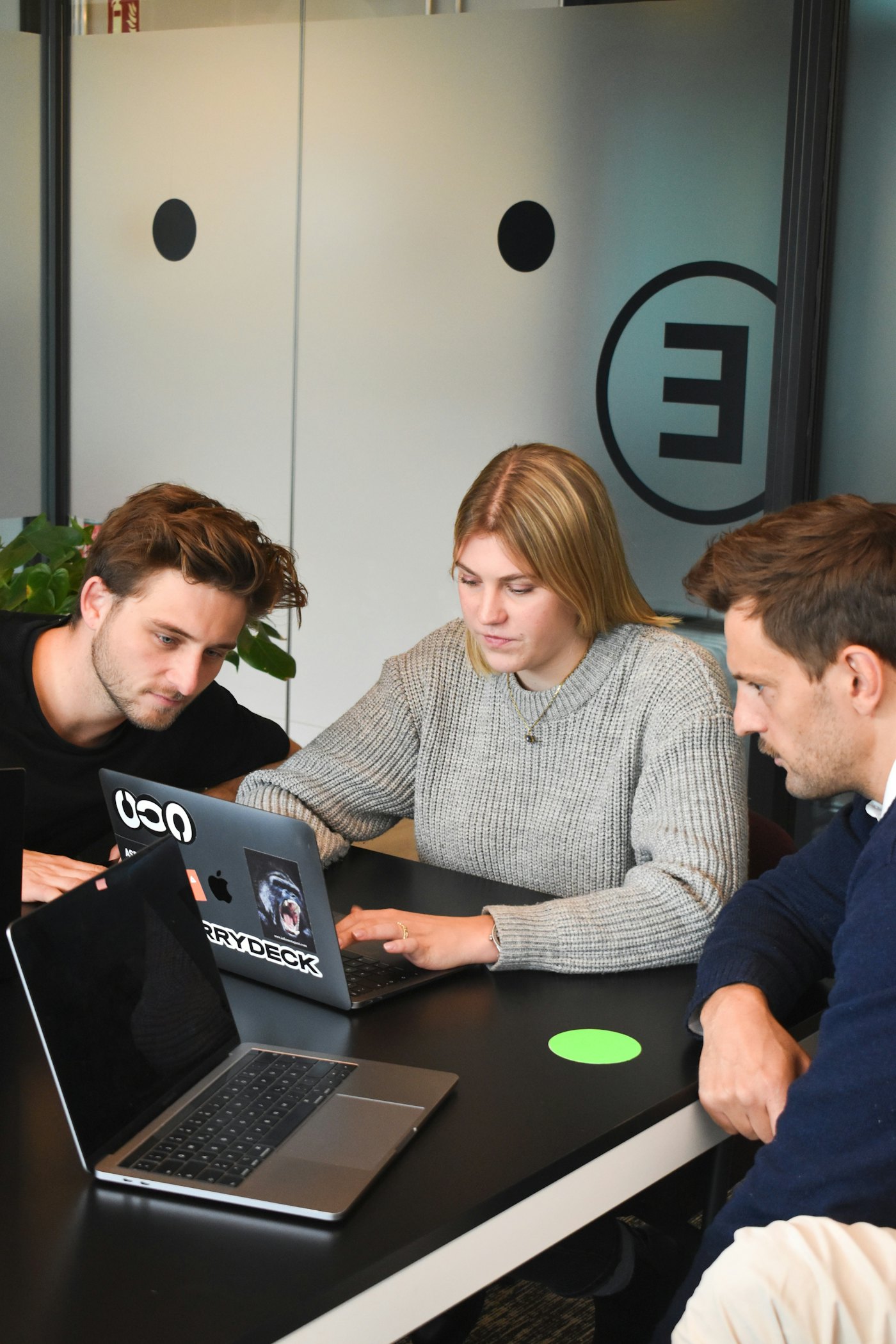Drei Kollegen lösen im Büro gemeinsam ein Problem an einem Laptop