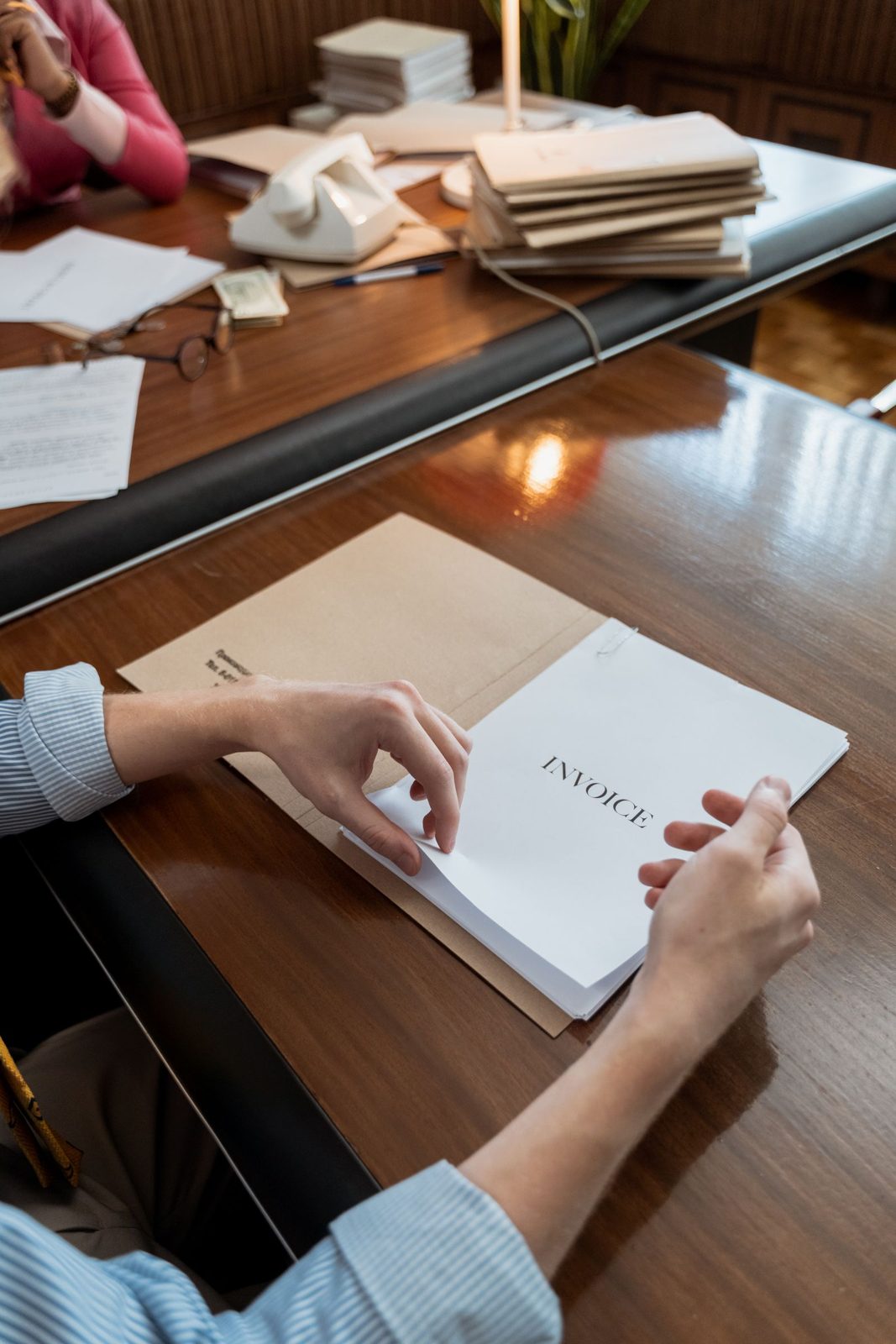 Hände sortieren einen Stapel Rechnungen auf einem Bürotisch