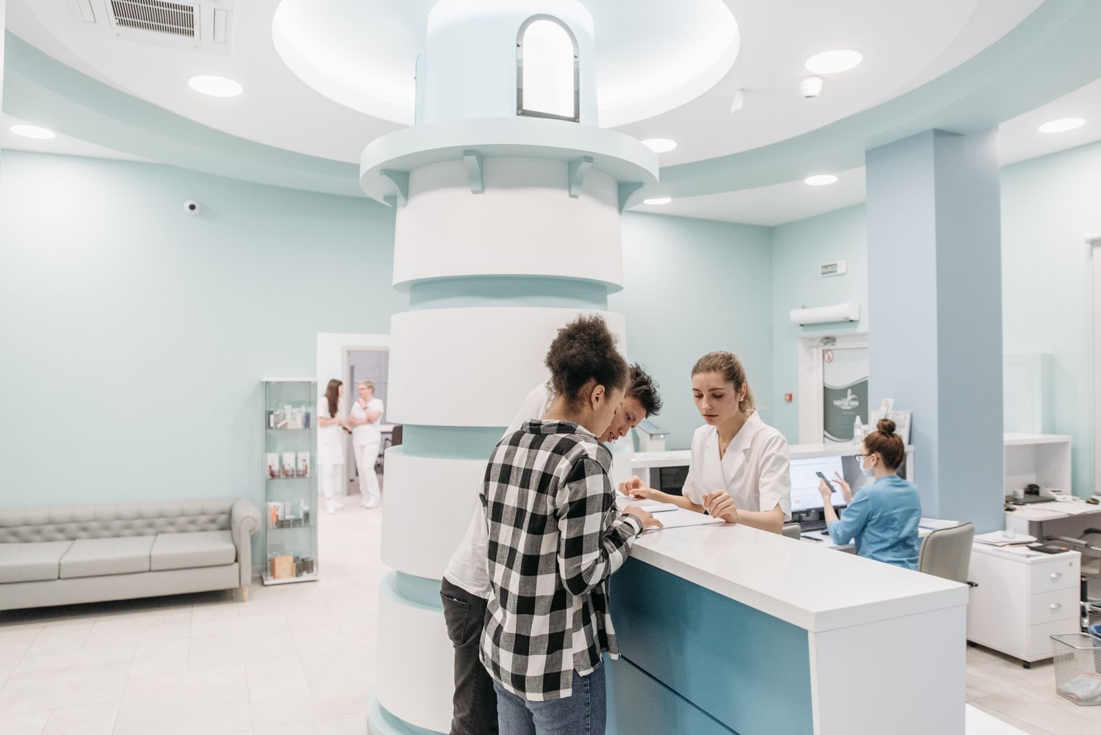 Patients registering with staff at a clinic reception desk