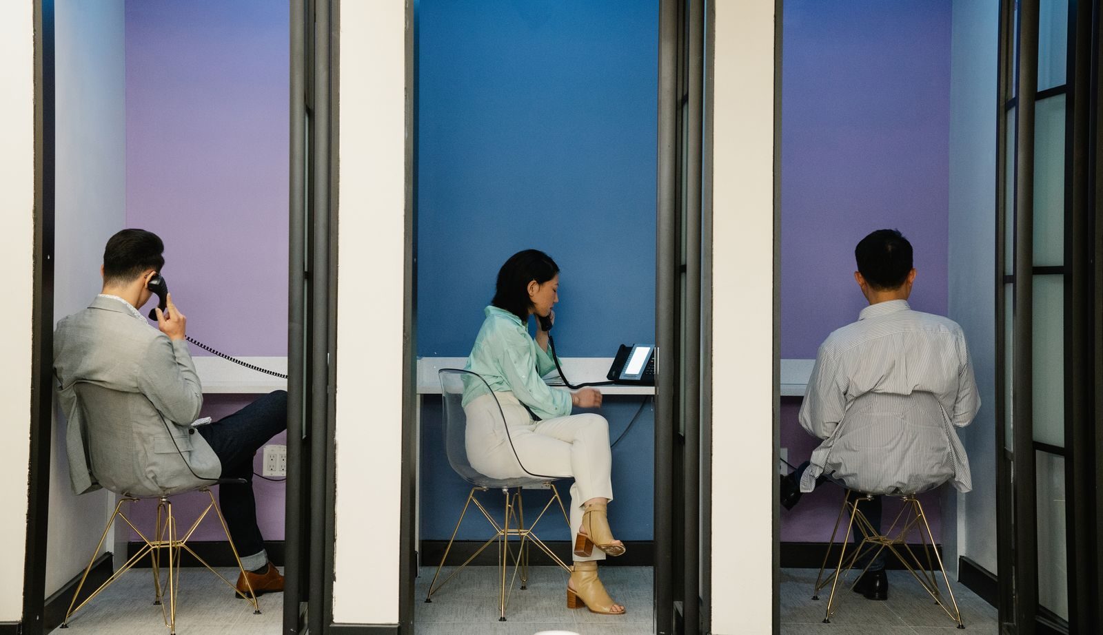 Sales reps on calls in phone booths in a modern office