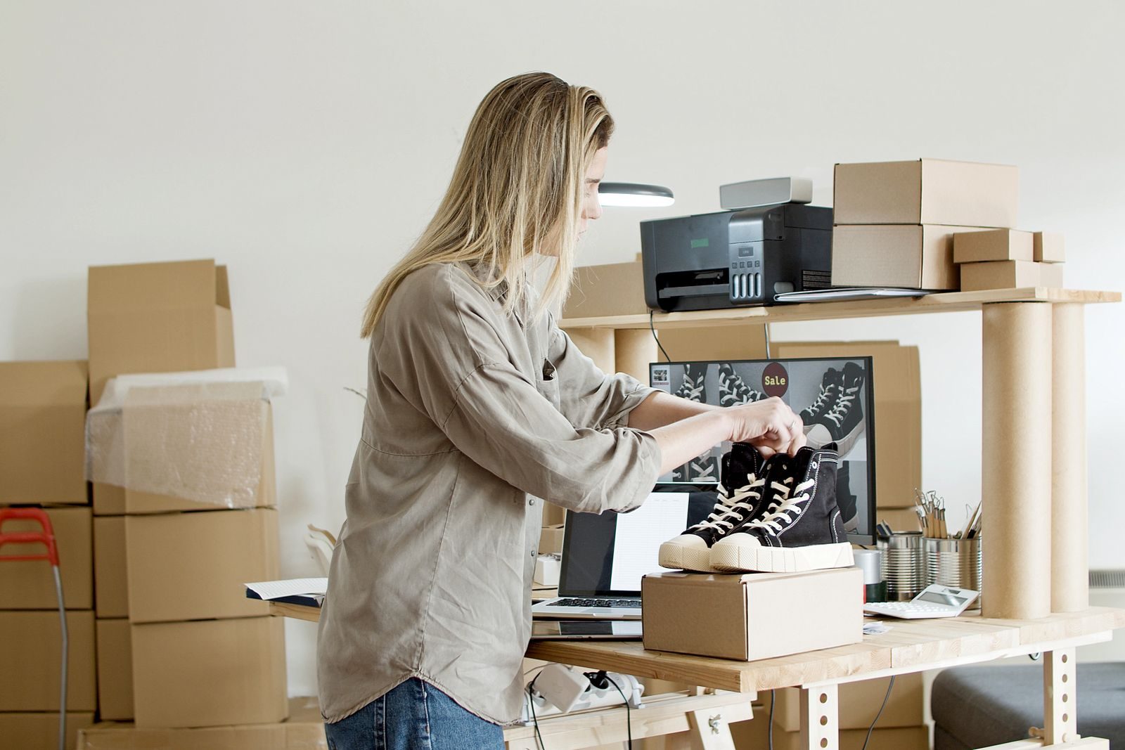 A shop owner packing an online order at her workbench